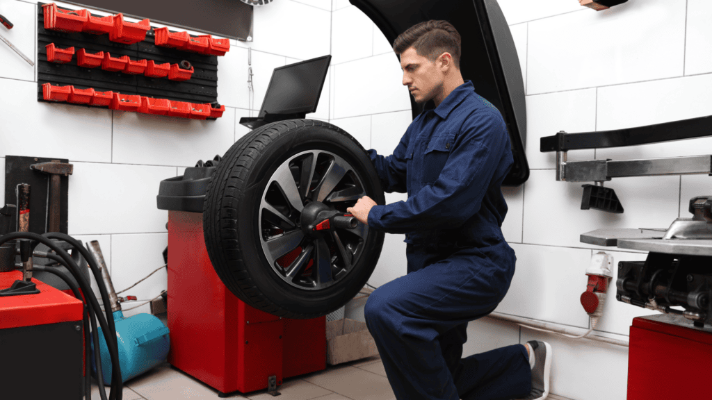 Technician removing wheel from wheel a balancer